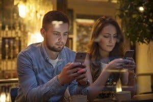 Dos personas jovenes manejan sus telefonos moviles